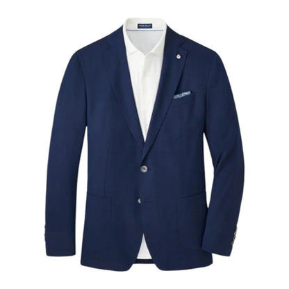 The Excursionist Flex Blazer by Peter Millar features a navy blue wool-silk blend with notch lapels, two front buttons, patch pockets, and a white dress shirt underneath. A pocket square peeks from the chest pocket.