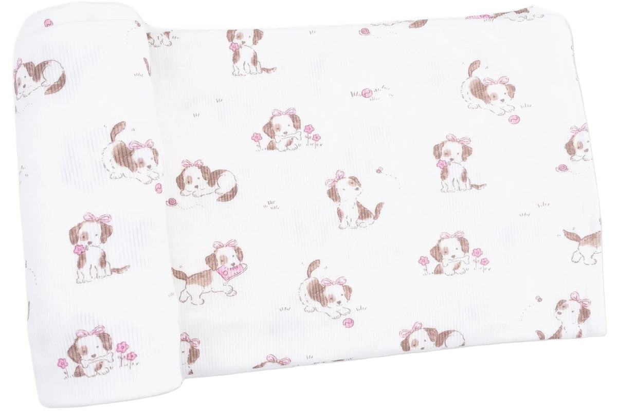 The Angel Dear Swaddle Blanket features a white background adorned with brown puppies wearing pink bows, holding flowers, and playing with pink balls. Crafted from viscose from bamboo, this blanket is soft and gentle against your baby’s skin.