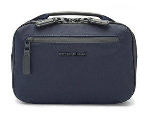 The Pursuit Travel Kit by Peter Millar is a small navy blue bag with a front zipper pocket, genuine leather trim, and the Peter Millar logo on the front.