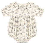 The Quincy Mae Baby Girls’ Collared Romper features a cream hue with puff sleeves, a ruffled collar, elastic leg openings, and a delicate floral print in grey and yellow tones.