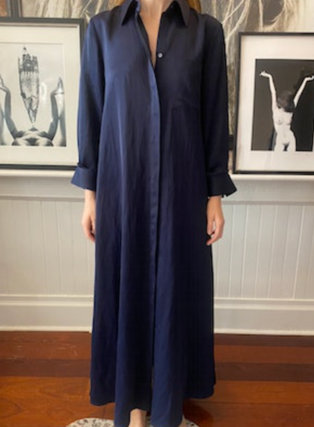 Clad in TWP's Jenny's Coated Linen Gown, a person stands elegantly in front of framed art.