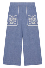 Louise Misha Girls’ Flofi Pants—wide-leg blue denim pants featuring white floral embroidery and lace trim on the front pockets, shown laid flat on a white background.