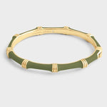 The Anabel Aram Bamboo Hinged Bangle features gold bamboo links, green enamel segments, and a sculpted design, shown against a plain light gray background.