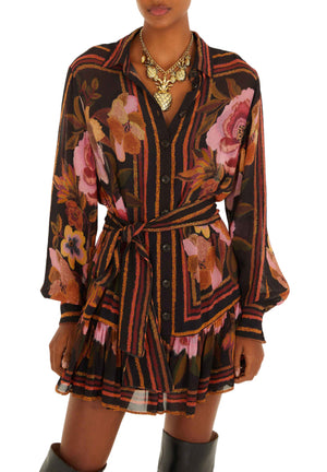 A person wears the Farm Rio Chenille Flowers Black Mini Dress, featuring a belted waist, button front, layered skirt, and floral-stripe design. The head is partly out of frame; a statement necklace completes the look.