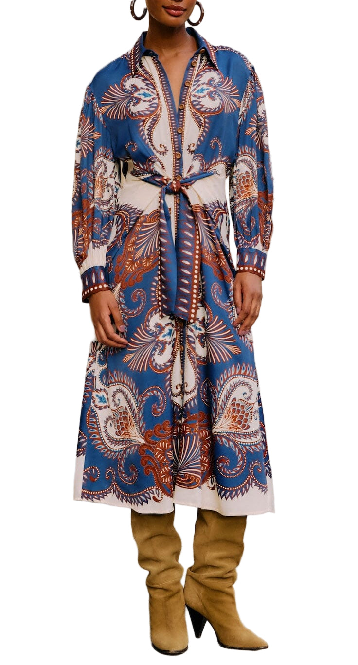 Woman wearing the Farm Rio Arabesque Scarf Blue Midi Dress, a long-sleeve, button-down midi with blue, white, and brown paisley patterns, a belted waist, paired with tan knee-high boots.