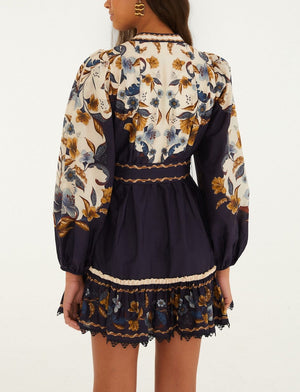 Back view of the Farm Rio Golden Nature Belted Mini Dress, featuring long puff sleeves, a belted waist, and a cream and navy blue floral pattern.