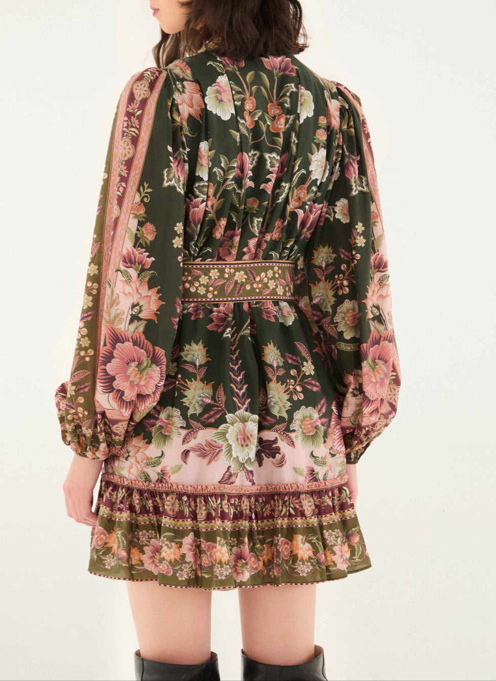 A woman faces away, wearing the Farm Rio Flowering Garden Tree Green Mini Dress featuring ruffled cuffs and hem—an ideal choice for a charming garden party.