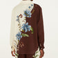 Back view of the Millena Winter White Shirt by Farm Rio, featuring an asymmetrical cream and brown color-block design with a botanical print of large blue flowers and green leaves.