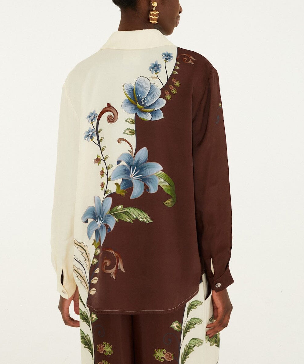 Back view of the Millena Winter White Shirt by Farm Rio, featuring an asymmetrical cream and brown color-block design with a botanical print of large blue flowers and green leaves.