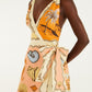 A woman models the Farm Rio Rio Souvenir Mixed Scarf Multicolor Mini Dress, a playful sleeveless mini dress featuring a vibrant tropical and seashell print, deep V neckline, and an oversized bow at the waist—perfect for adding flair to any summer wardrobe.