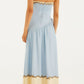 A woman stands with her back to the camera, radiating resort elegance in the Farm Rio Rio Souvenir Mixed Scarf Multicolor Maxi Dress, styled with brown platform sandals and gold earrings against a plain background.