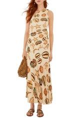 Dressed in the Farm Rio Marine Shells Sand One Shoulder Maxi Dress, she pairs the cream-colored, marine shell-adorned silhouette with a woven bag and flat sandals—perfect for any summer occasion.