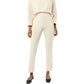 A person wearing the Ann Mashburn Faye Flare Cropped Pant and a cream long-sleeve top with black flats stands against a white background.