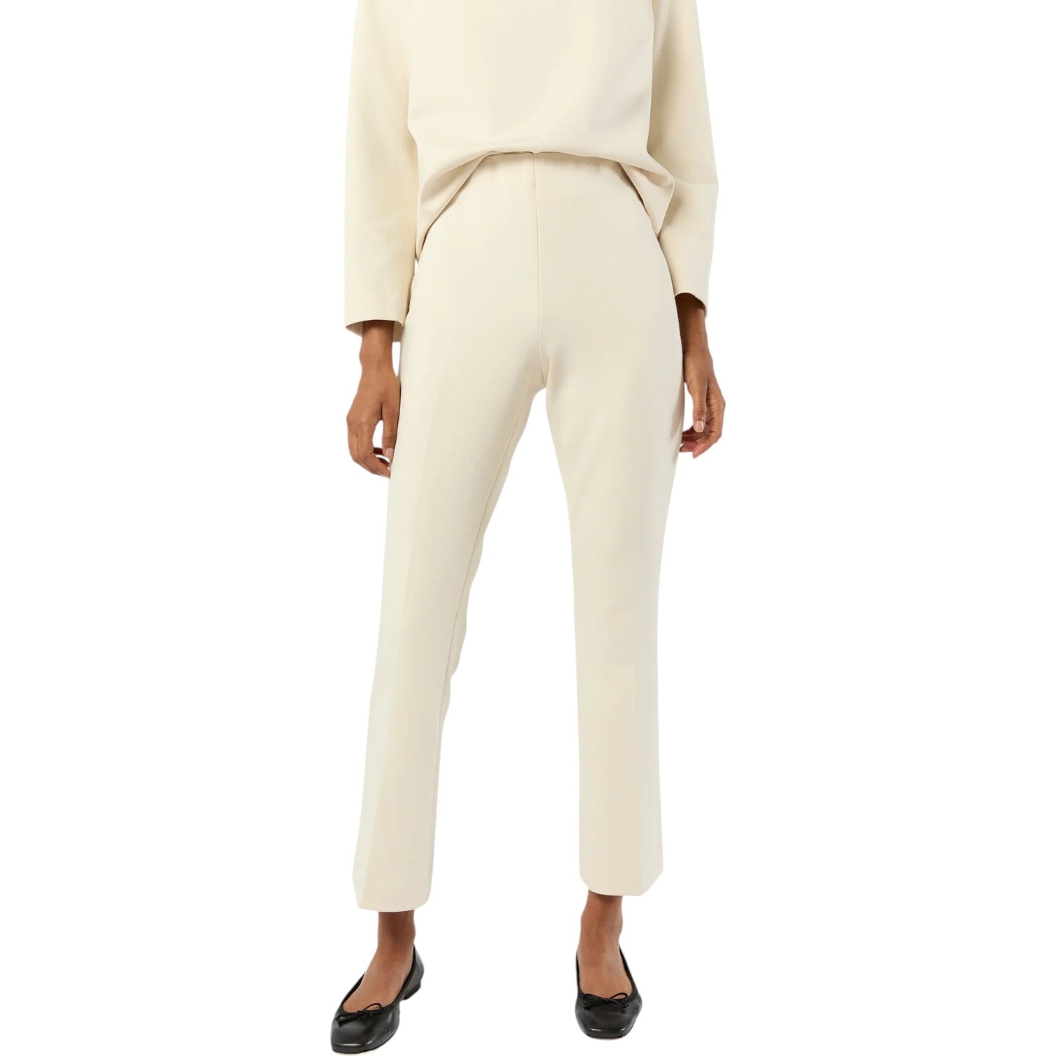 A person wearing the Ann Mashburn Faye Flare Cropped Pant and a cream long-sleeve top with black flats stands against a white background.
