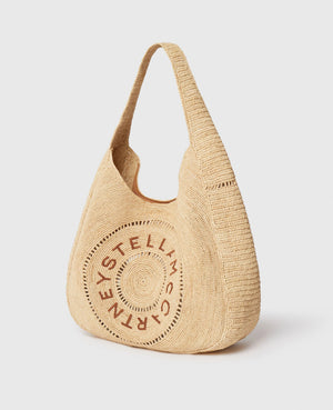 The Stella McCartney Logo Raffia Slouchy Large Tote Bag features beige woven raffia, a curved handle, and a circular front logo—blending vegan, eco-conscious craftsmanship with chic style.
