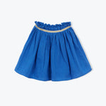 The Girls' Fotini Skirt by Arsene & Les Pipelettes is a blue, knee-length flared skirt with a ruffled elastic waistband and thin gold trim near the top, shown against a plain background.