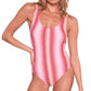 A person poses confidently in the Lemlem Haset One Piece, a pink and red striped swimsuit crafted from scrunch rib fabric. With one hand on their hip, they exude vibrant charm against a plain backdrop, embodying the signature style of Lemlem swimwear.