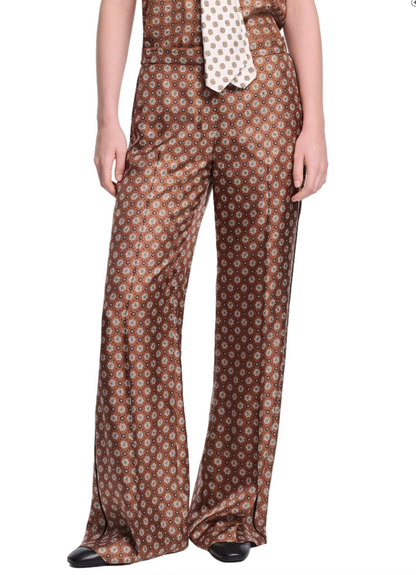 Someone wears Dorothee Schumacher’s Graphic Dreams Pants—brown straight leg with a signature tie print—and a matching sleeveless top, posing against a white background.