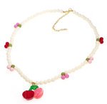 Add a touch of spring to your look with the Cherry Pink & Red Pearl Necklace by Lillies & Roses—a beaded necklace featuring delicate white, pink, and green beads, a playful cherry-shaped pendant, and an adjustable gold clasp.