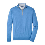 The Peter Millar Excursionist Flex Quarter-Zip Sweater, shown in light blue on a white background, features Merino wool, a stand collar with partial zipper closure, and a visible checked shirt collar detail underneath.