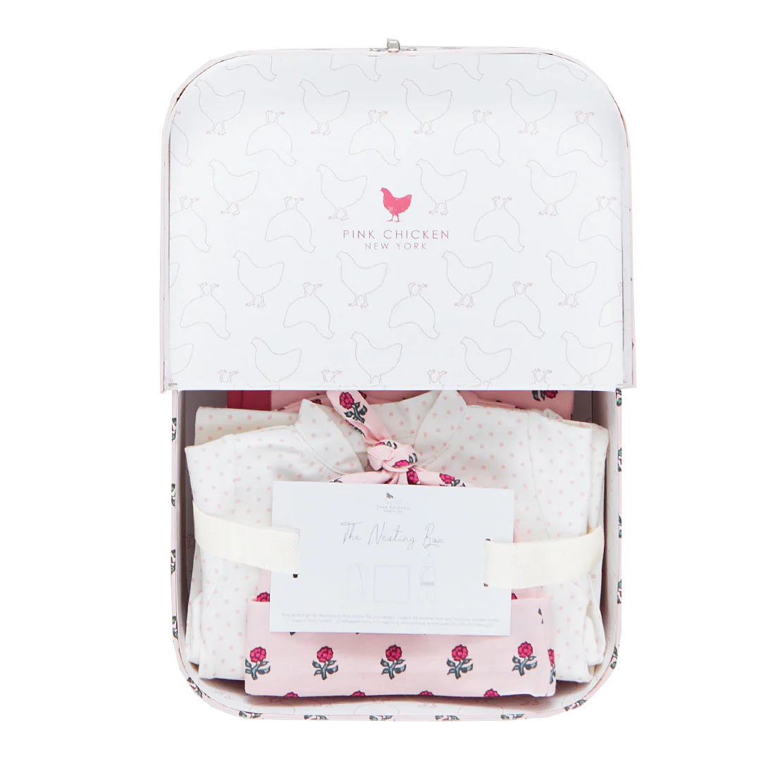 The Pink Chicken Nesting Box Baby Take Home Set features folded pink and white organic pima cotton newborn clothing in a white gift box with a chicken pattern and includes "The Welcoming Box" card—perfect for bringing baby home in comfort and style.