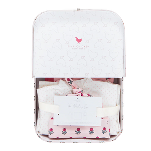 The Pink Chicken Nesting Box Baby Take Home Set features folded pink and white organic pima cotton newborn clothing in a white gift box with a chicken pattern and includes "The Welcoming Box" card—perfect for bringing baby home in comfort and style.