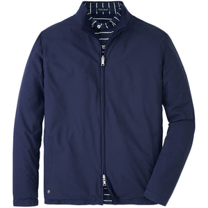 The Peter Millar Ryder Reversible Jacket, a navy blue water-resistant style with a high collar, is shown layered over a navy and white striped shirt.