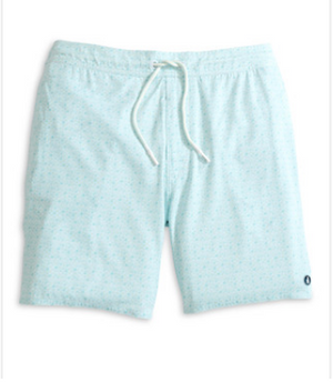 The Anemone Swim Trunks by Johnnie-O are light blue surf shorts made from a comfortable poly/spandex blend, featuring a subtle pattern, a white drawstring, and a small circular logo near the bottom hem on the left leg.