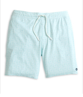 The Anemone Swim Trunks by Johnnie-O are light blue surf shorts made from a comfortable poly/spandex blend, featuring a subtle pattern, a white drawstring, and a small circular logo near the bottom hem on the left leg.