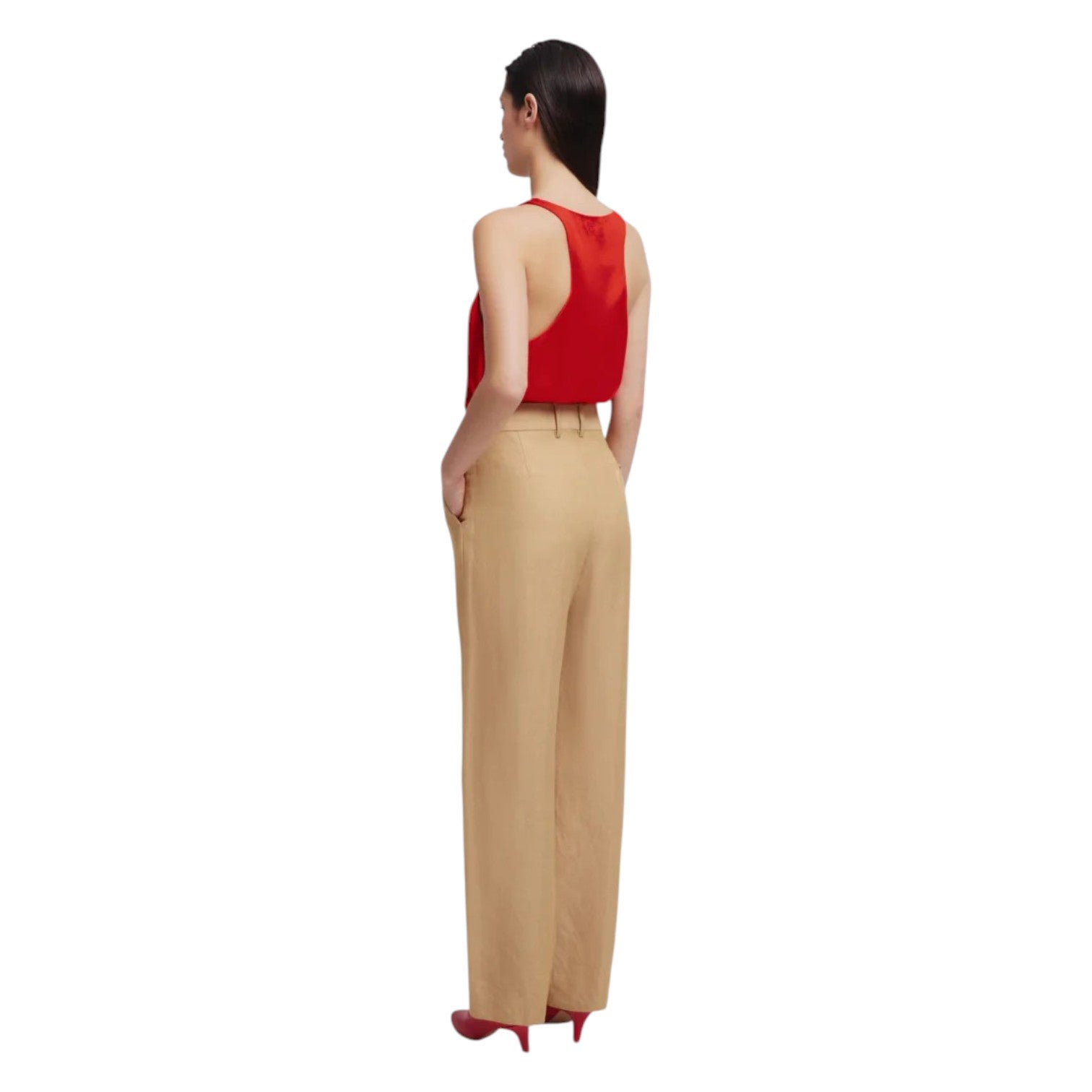 A woman stands with her back to the camera in a red sleeveless top, beige Renegade Fox Pants by Blaze Milano, and red heels against a white background.