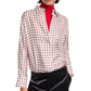 A person wears the Dorothee Schumacher Graphic Dreams Blouse—a relaxed fit, white silk twill shirt with a red geometric pattern—over a red turtleneck and black pants.