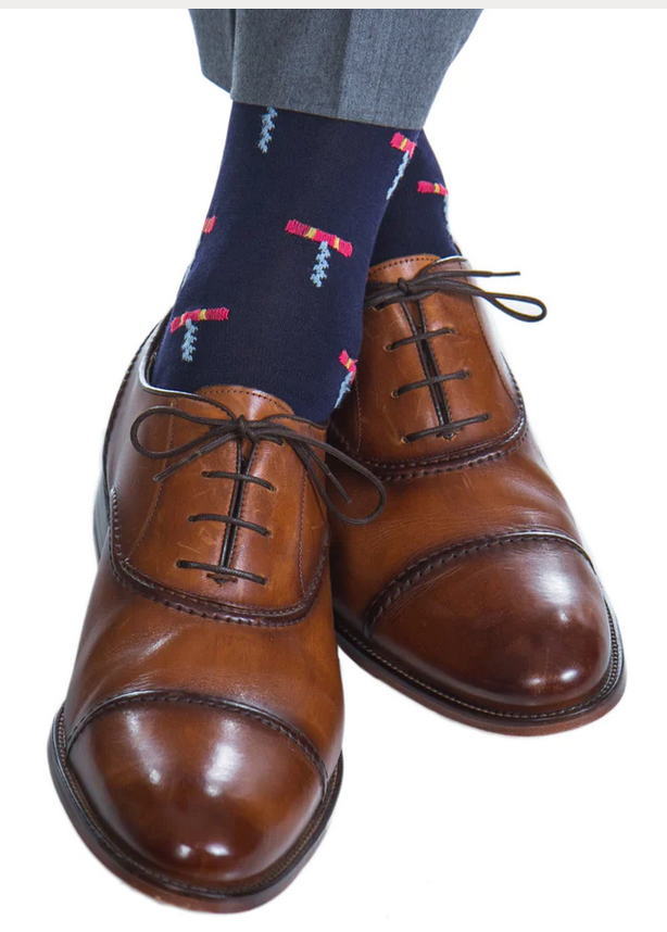 Brown leather dress shoes with black laces, paired with Dapper Classics Cork Screw Mid Calf Socks in navy and coral. The breathable socks complement the sophisticated attire of gray pants.