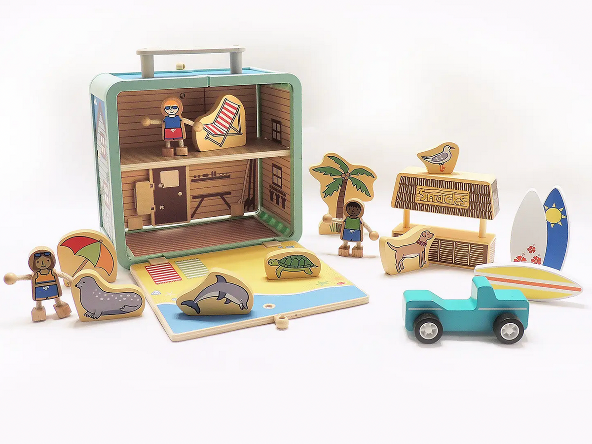 Jack Rabbit Creations Suitcase Series wooden playset that opens into a beach house, featuring eco-friendly bamboo pieces, wooden figures, a snack stand, surfboard, and toy truck with non-toxic paints.
