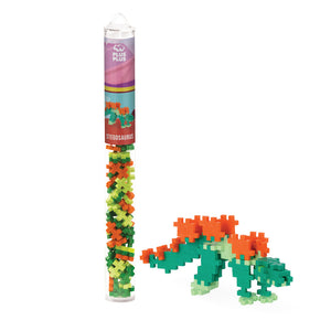 The Plus Plus Tube - Stegosaurus features a clear tube with colorful interlocking pieces for creative play and fine motor skill building, shown beside a completed Stegosaurus model made from the set.