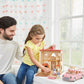 A man and a girl play with a Calico Critters dollhouse set near a window, which features animal figurines, picnic accessories, and the Calico Critters Family Picnic Van.
