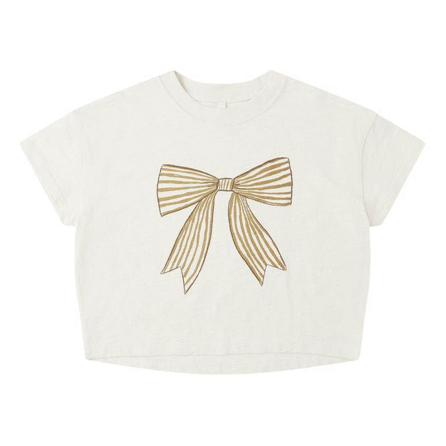 Rylee & Cru’s Baby Girls' and Girls' Boxy Tee features a white short-sleeve design with a large gold ribbon bow graphic on the front and a classic crew neckline for a relaxed, boxy fit.