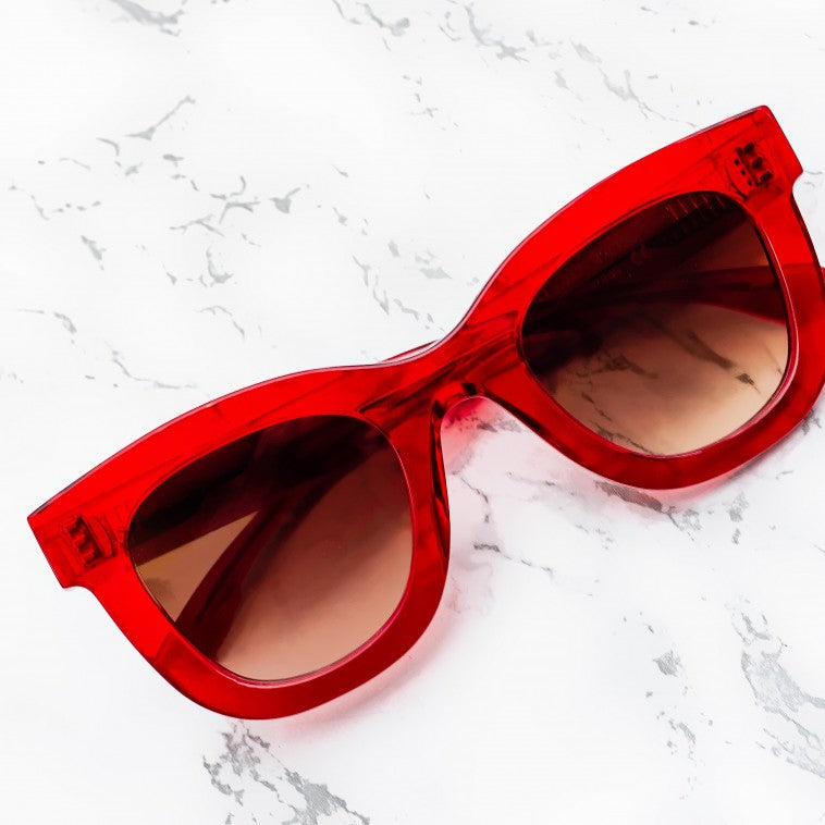 Thierry Lasry Gambly Sunglasses with dark lenses and a sleek rectangular frame, providing UV protection, rest elegantly on a white, marbled surface. Handcrafted in Italy by Thierry Lasry.