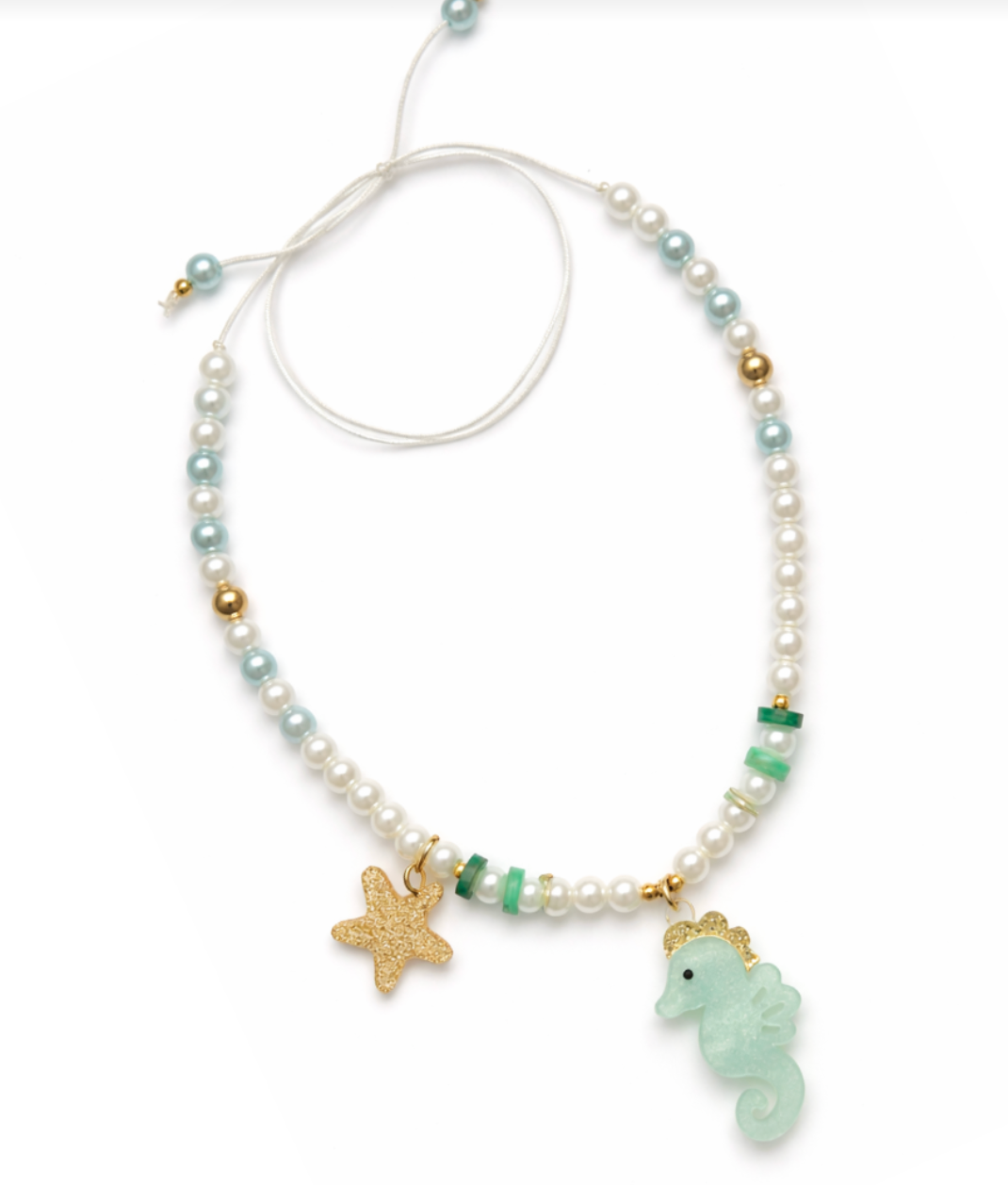 Introducing the Seahorse Green Necklace by Lillies & Roses, a handcrafted piece featuring white, blue, and gold beads, beautifully accented with a gold starfish charm and a light blue seahorse pendant on a white adjustable cord.