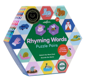 The Eeboo Rhyming Words Hexagon Pairing Puzzles come in a hexagonal box adorned with Sarah Walsh’s charming illustrations of animals and objects. Designed for ages 3 and up, this engaging pre-literacy activity helps children build essential skills, with the packaging featuring example pairs such as “tea” and “bee.”.