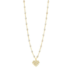 The Gigi Clozeau In Love Diamond Necklace 16.5" features yellow gold with small white opal resin pearls and a heart pendant studded with clear stones, elegantly displayed on a plain white background.