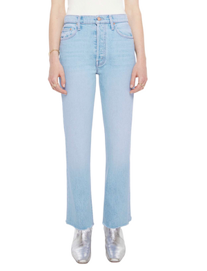 A person wears Mother’s The Tripper Flood Fray light blue high-rise flare jeans, a white top, and silver ankle boots, standing against a plain white background.