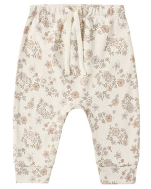 Quincy Mae’s Baby and Kids’ Drawstring Pant in cream is crafted from soft organic brushed jersey, featuring an elastic waistband and adorned with a delicate pattern of small, muted pastel flowers and leaves.