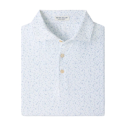 The Peter Millar On The Line Performance Jersey Polo is a neatly folded white polo shirt featuring a subtle blue floral pattern and three light-colored buttons, crafted with four-way stretch for all-day comfort.