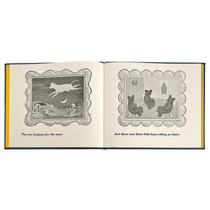 Open Graphic Image leather-bound children's book showing two illustrated pages; left side depicts a cow jumping over the moon, right side shows three little bears on chairs.