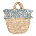 The Girls' Pénelope Smocked Raffia Bag by Kidiwi features short handles and a ruffled blue and white floral trim, inspired by classic patchwork prints.