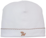 The Kissy Kissy Premier Puppy Paws Hand Emb. Hat is a white baby hat made from soft Peruvian cotton, adorned with a delicate hand-embroidered brown dog and a decorative brown stitched line near the brim.