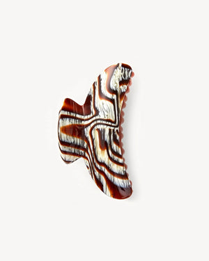 The Machete Grande Heirloom Claw, crafted from Italian acetate, showcases a marbled black, brown, and white zebra-like pattern—ideal for securing full updos against a plain white background.