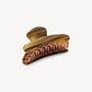 Introducing the Grande Heirloom Claw by Machete—a brown and amber marbled hair claw clip, expertly crafted from luxurious Italian acetate. Featuring a curved design with interlocking teeth, it’s ideal for securing long, thick, or voluminous hair. Shown against a plain white background.