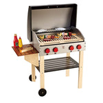 A Hape Gourmet Grill wooden toy grill set with various play food items, including hot dogs, hamburgers, kebabs, and condiments. It features four red control knobs, a side shelf with ketchup, mayonnaise, and mustard, and double-sided grates for the ultimate gourmet grill experience.