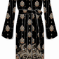 The Viv Midi Dress by Cara Cara is a long black dress adorned with a paisley and floral pattern in beige and gold tones, featuring a waist belt and wide sleeves for an elegant touch reminiscent of a V-neck popover style.